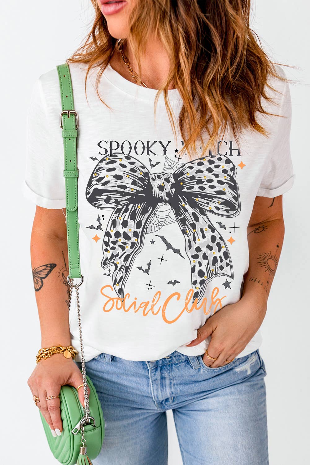 Halloween spooky witch social tee with witch graphic and leopard bow, styled with jeans for festive flair.